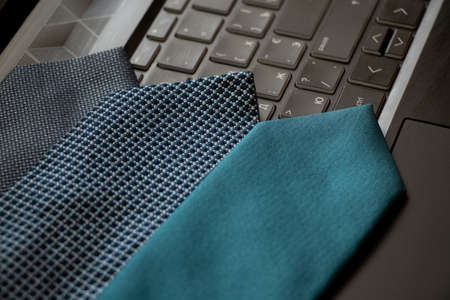 Three blue ties lie on a black laptop on the desk at home, work online, businessの写真素材
