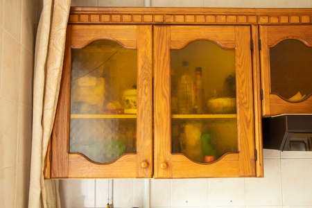 Old brown wooden kitchen cabinet with glass doors in the kitchen at home, kitchen furnitureの写真素材