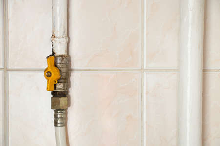 A gas pipe with a faucet against the background of a tile at home in an apartment, a faucet on a pulp pipe in the kitchenの写真素材