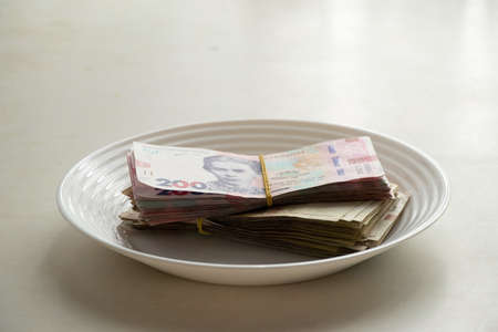 Ukrainian one hundred and two hundred hryvnia lie on a plate on the table in the...
