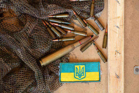 Pili lie on a green cloth on a board and next to it lies a stripe with the flag of Ukraine, the war in Ukraine, ammunition and weaponsの写真素材