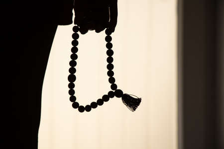 Rosary in the hands of a woman in the dark, faith and religionの写真素材