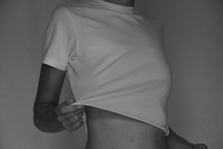 A girl in a white t-shirt stretches her t-shirt with her hand on an isolated background, a black and white photo of a white t-shirt on a girl, women's clothingの写真素材