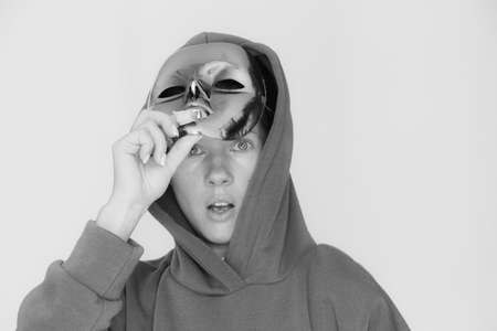 The girl removes a plastic mask from her face and is surprised on an isolated background, black and...