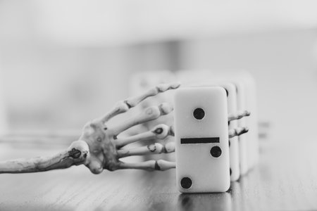 Skeleton hand and domino bones are on the table, black and white photo, death game, gamblingの写真素材