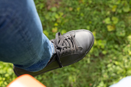 Men's legs in black sneakers and jeans on a green background of grass in Ukraine, men's legs and...