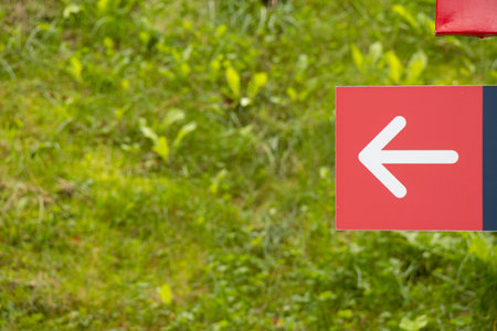 Red arrow to the left on the background of green grass in the park, turn to the leftの写真素材