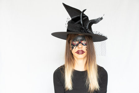 The image of a witch, witch makeup on the face of a girl and a hat of a witch, Halloween, a portrait...