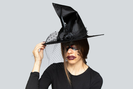 The image of a witch, witch makeup on the face of a girl and a hat of a witch, Halloween, a portrait...