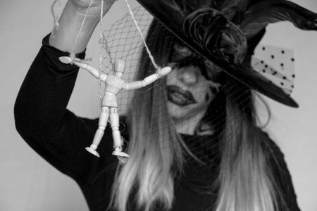 The witch holds a wooden doll of a man on the ropes, manipulation of people and power, magic and tyranny, weak-willed peopleの写真素材