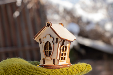 a small wooden house in the hands of a girl in the winterの写真素材