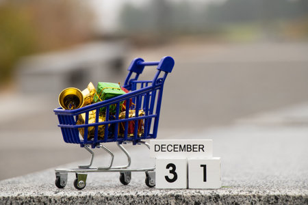 December 31 is written on a wooden plate in the calendar, and next to it is a cart from a supermarket with gifts on the street, happy new year, new year holidayの写真素材
