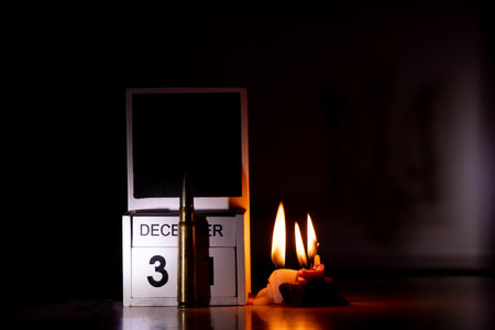 December 31 is written on wooden cubes and a combat bullet on a table in the dark, candles, Happy...