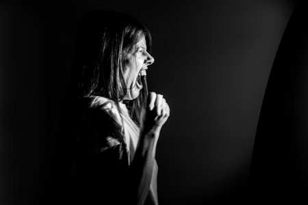 The girl screams in the dark from anger and rage, pain and screamの写真素材