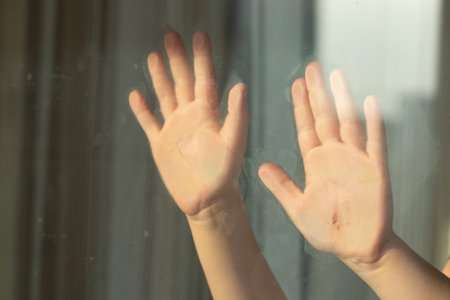 Children's hand with a notch on the glass during quarantineの写真素材