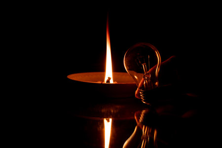A rope in oil lies on a plate and burns, and next to it lies a light bulb on the mirror in the dark,...
