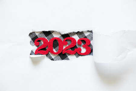 2023 on the background of torn white paper, happy new year 2023