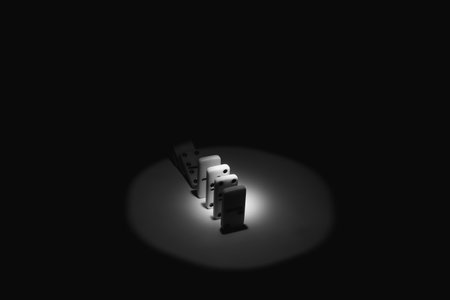 Dominoes on a table in the dark with a beam of light, black and white photo, play dominoes close upの写真素材