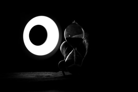 An old female hand holds an hourglass in the dark at the table, time goes by, the speed of life