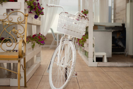 a white bicycle with a flower box stands near a coffee shopの写真素材
