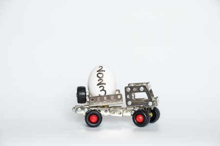 A chicken white egg with the text 2023 lies to a childrens car from an iron constructor on a white background, transportation of products, businessの写真素材