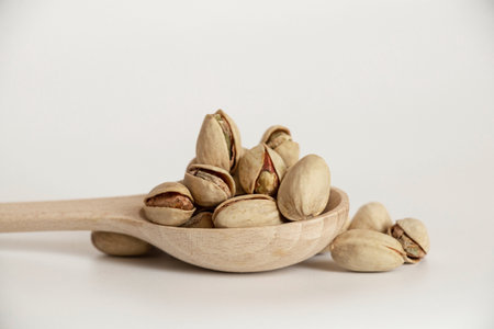 Bunch of pistachios in a wooden spoon on a white backgroundの写真素材