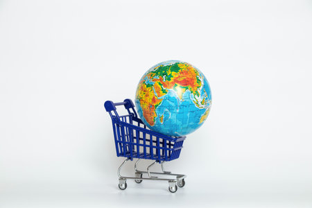 Supermarket trolley and globe on white background close-up, international tradeの写真素材
