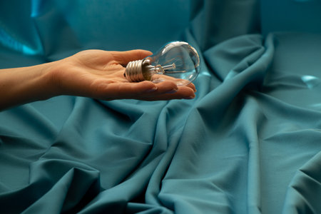 An incandescent lamp in the hands of a girl on a blue background