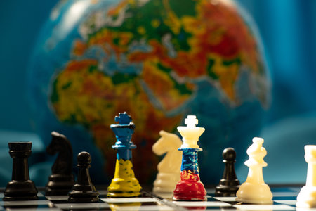 Chess kings in the colors of the flag of Ukraine and the flag of Russia on a chessboard against the backdrop of the globe, chess and chess games, politicsの写真素材