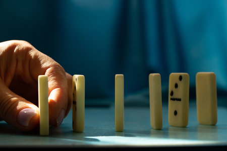 Female hand and dominoes on a blue backgroundの写真素材