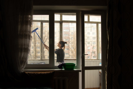 The girl washes the window in the apartment, cleaningの写真素材