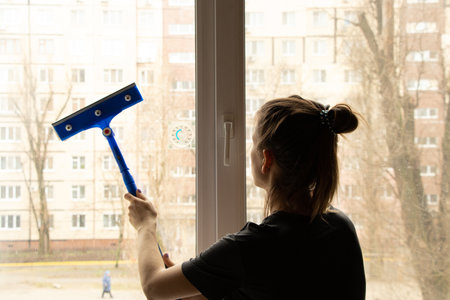 The girl washes the window in the apartment, cleaningの写真素材
