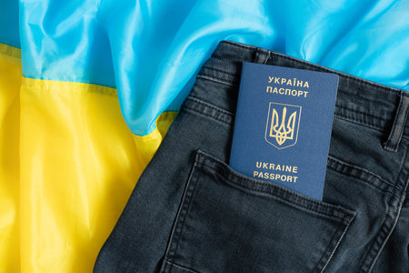 A foreign biometric Ukrainian passport lies in a jeans pocket against the background of the flag of Ukraineの写真素材
