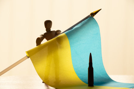A bullet stands on the flags of Ukraine and a wooden man holds a flag in the sunlight, warの写真素材