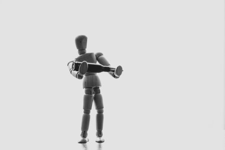 Wooden puppet man holding a bullet in the sunlight close-upの写真素材