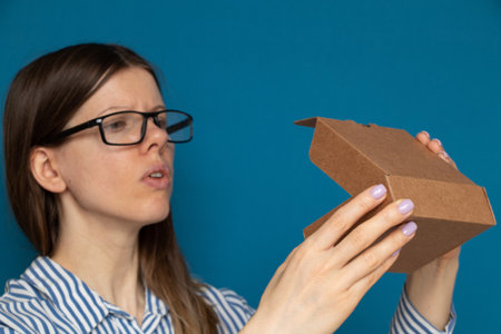 The girl opens a cardboard box on a blue background, a boxの写真素材