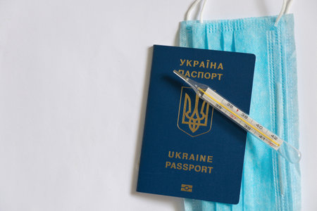 medical thermometer lies and a medical mask on a Ukrainian foreign passportの写真素材
