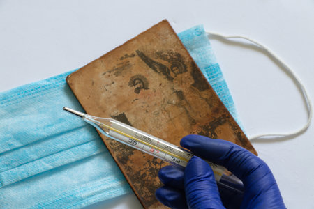 glass thermometer and hand in blue glove close-up on the background of the Medetsyn maskの写真素材