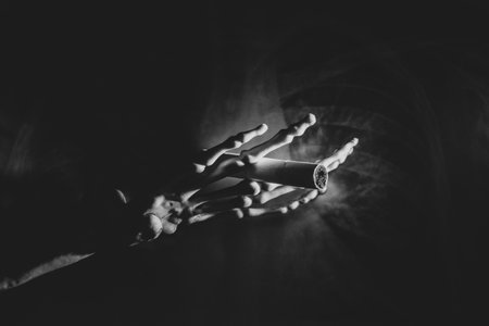 Skeleton hand with a cigarette on an x-ray photo of the lungs in the dark, smoking and harm to health, black and white photoの写真素材