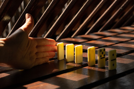 Women's hand and dominoes on a wooden table in the sun in the parksの写真素材
