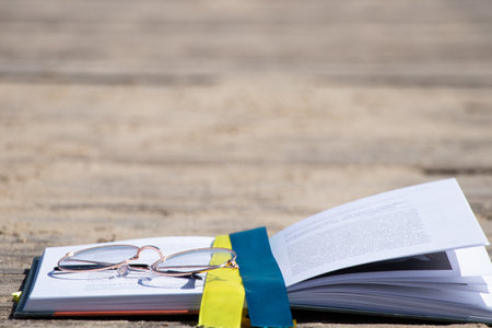 A book with a ribbon of the flag of Ukraine and glasses lies on the banks of the Dnieper River in Ukraine, education in Ukraineの写真素材