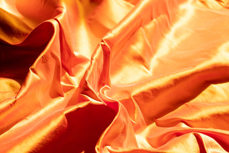 Golden wavy fabric in the sun as a background, golden fabricの写真素材