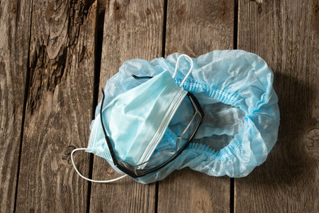 medical cap glasses mask lie on a wooden table, doctor's uniformの写真素材