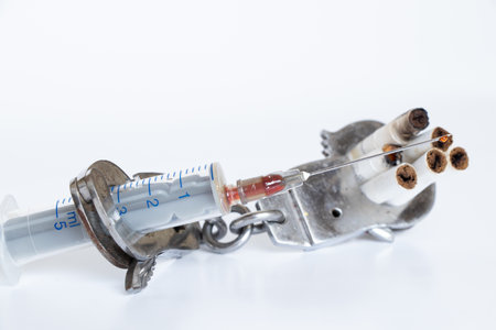A syringe and cigarettes are handcuffed on a white background, drug addiction, a bad habitの写真素材