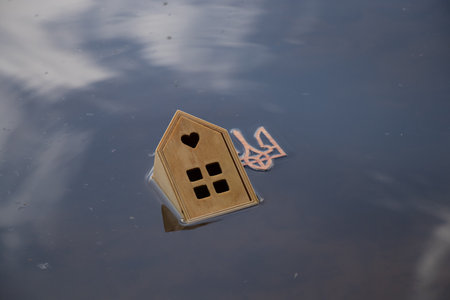 A small wooden house floats along the Dnieper River in Ukraine in the sun and the coat of arms of...