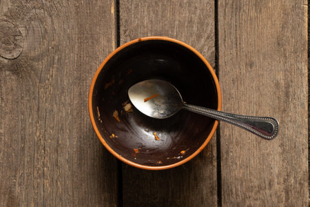 dirty brown plate after meal and spoon on old wooden table close upの写真素材