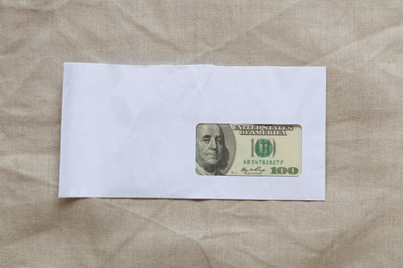 White envelope and one hundred dollars lie in an envelope on an isolated background, business