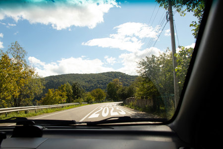 View from the car on the road where 2023 and 2024 are written on the road to the Carpathians in Ukraine, the road with a turn and the beginning of a new path, the futureの写真素材