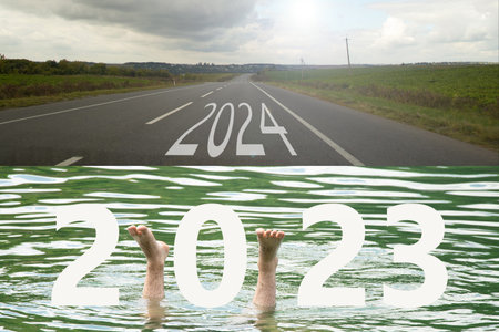 Man's feet drown in the river with the text 2023 and the road with the text 2024 in Ukraine, a new path next year 2024, ups and downs in lifeの写真素材