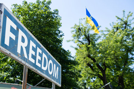 The word freedom is written on a road sign against the background of the flag of Ukraine in the city of Dnipro in Ukraine during the war days..の写真素材